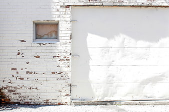 White brick wall with peeling paint and large garage door