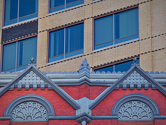 Red brick building facade with gray ornate details and blue windows