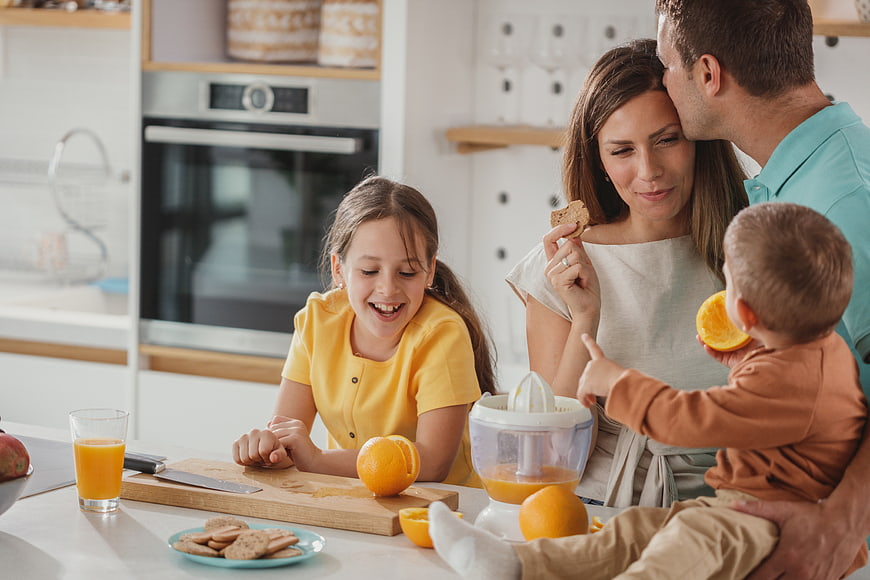 Happy family making fresh orange juice in modern kitchen