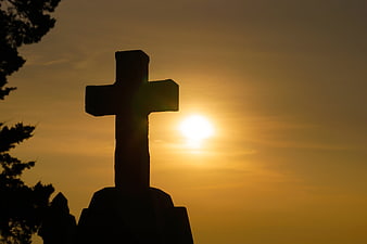 Silhouette of Christian Cross Against Golden Sunset Sky