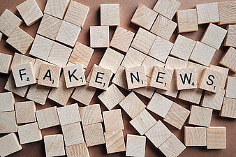 Fake News spelled with wooden letter tiles on brown background