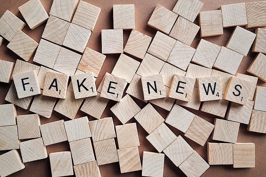 Fake News spelled with wooden letter tiles on brown background