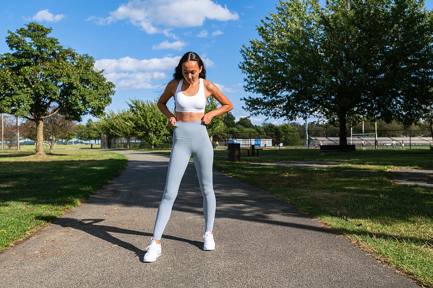 Woman adjusting leggings on park path