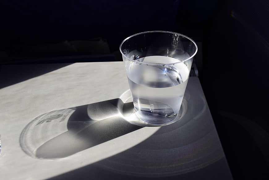 Glass of water with caustic light patterns on white surface