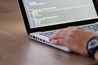 Close-up of hand typing code on laptop keyboard