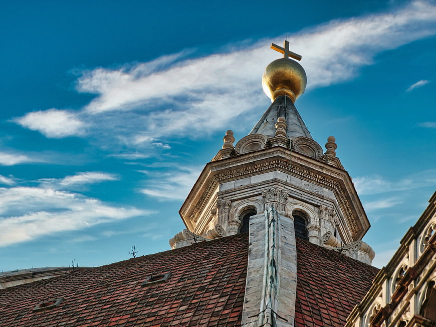Golden church spire with cross against blue sky