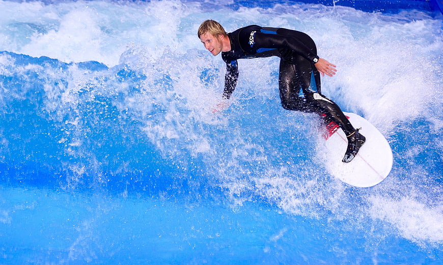 Man surfing on artificial wave in wetsuit