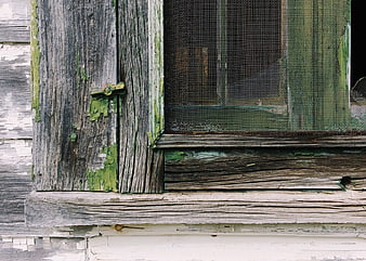 Close-up of weathered wooden window frame with peeling green paint