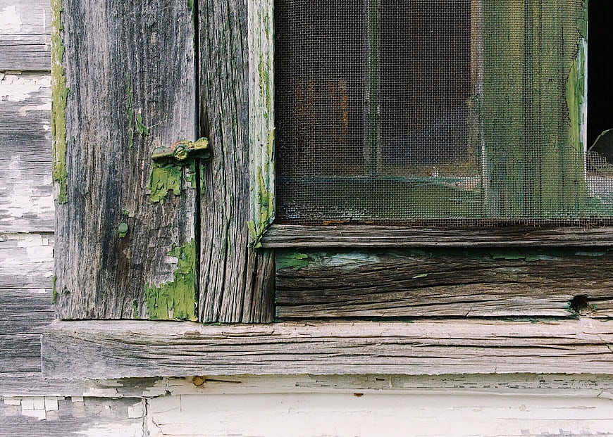 Close-up of weathered wooden window frame with peeling green paint