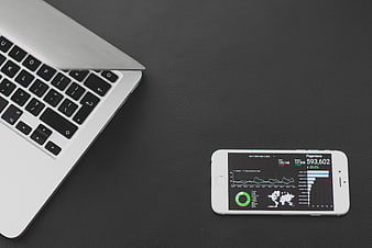 Laptop and smartphone displaying analytics dashboard on dark desk