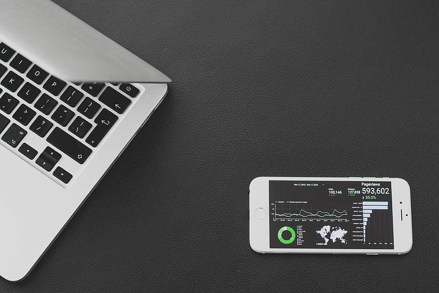 Laptop and smartphone displaying analytics dashboard on dark desk