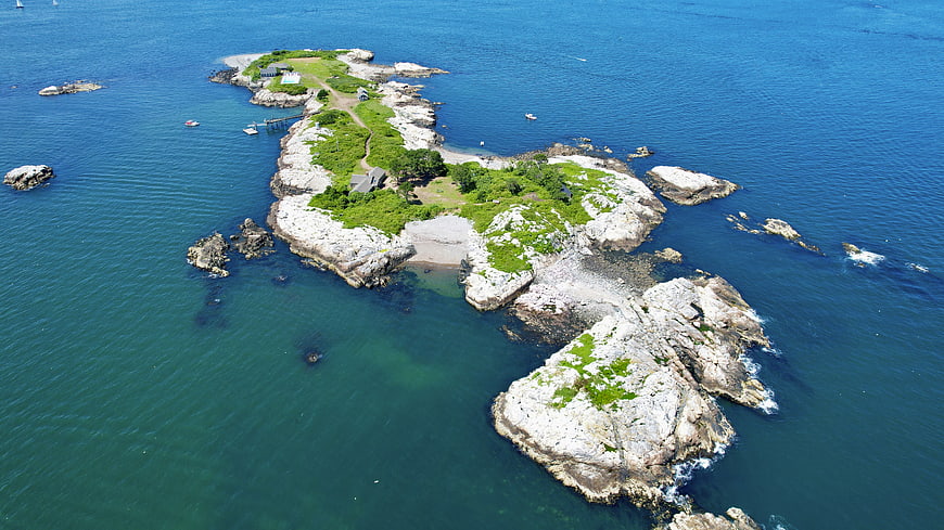 Aerial view of rocky island with green vegetation and blue ocean