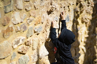 Young child climbing a textured stone wall outdoors