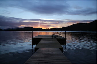 Serene Wooden Dock on Lake at Sunset with Mountains
