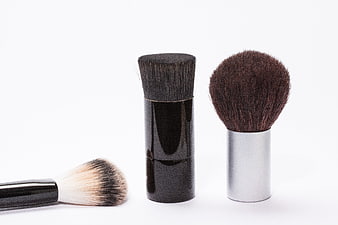 Three makeup brushes with black and silver handles on white background