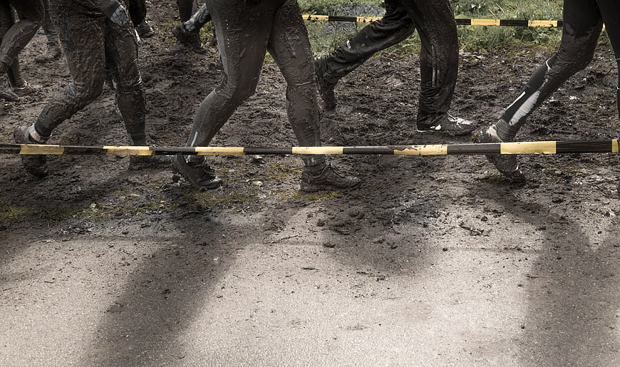 Muddy legs running through obstacle course race