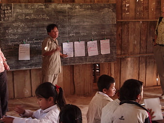 Rural classroom scene with teacher instructing students in Laos