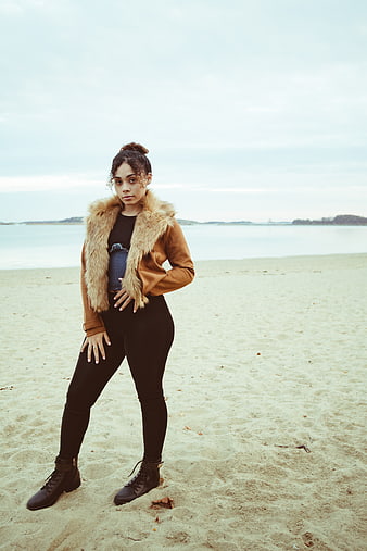 Stylish Woman in Fur Jacket Standing on Sandy Beach