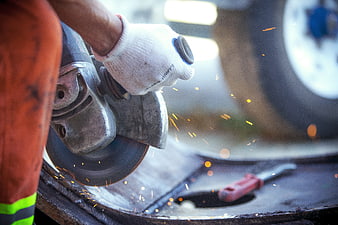 Worker grinding metal with angle grinder and sparks
