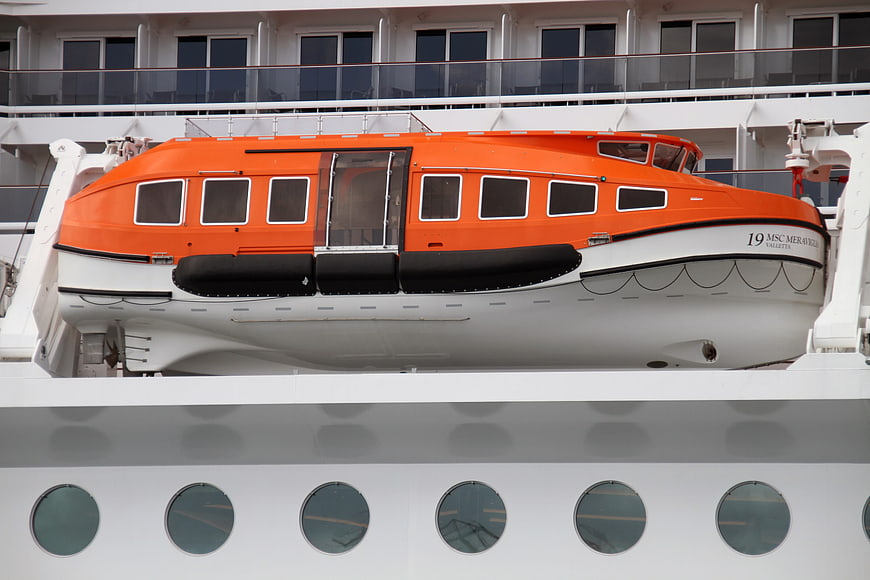 Orange lifeboat on white cruise ship deck