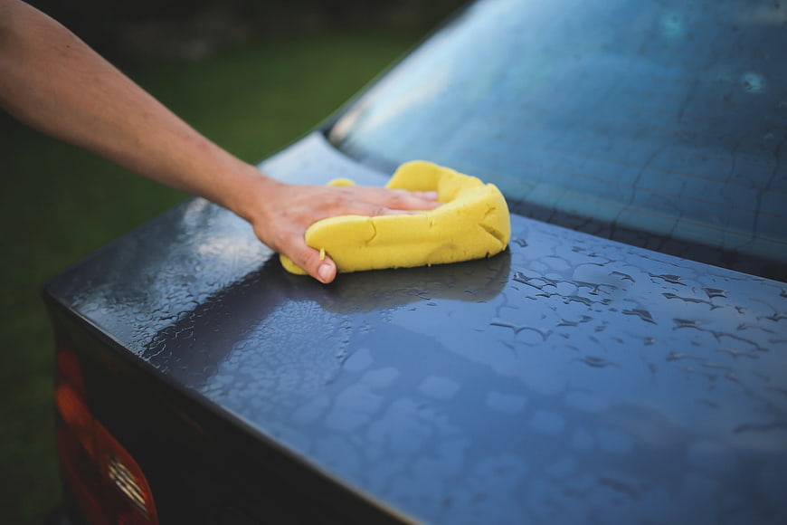 Hand washing car with yellow sponge