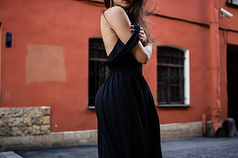 Woman in Black Dress Against Red Wall