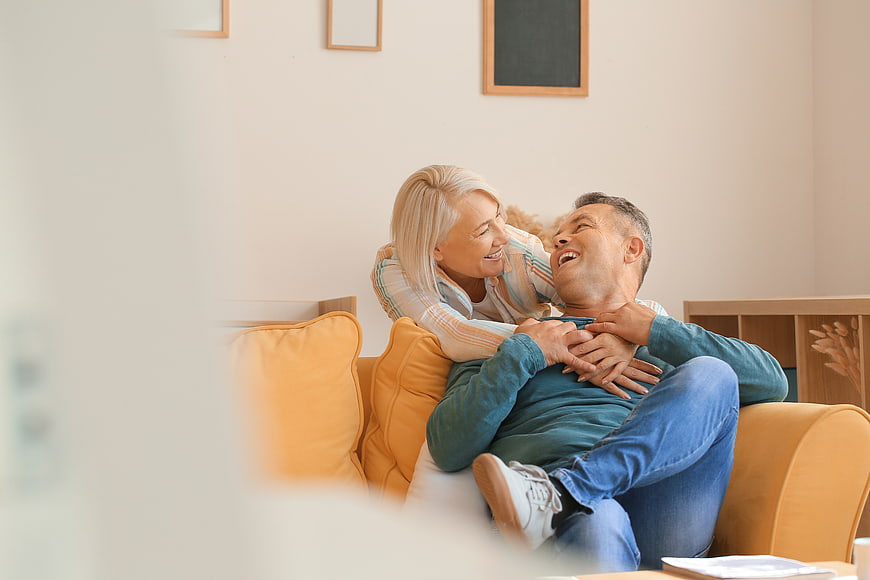 Happy Senior Couple Laughing Together on Sofa at Home