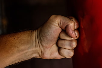 Close-up of clenched fist gripping red boxing glove
