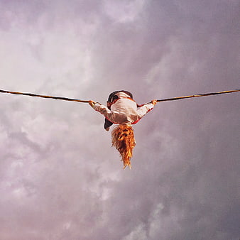 Woman Hanging Upside Down on Rope Against Cloudy Sky