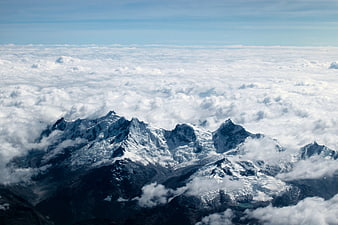 Aerial View of Snowy Mountain Peaks Above Clouds