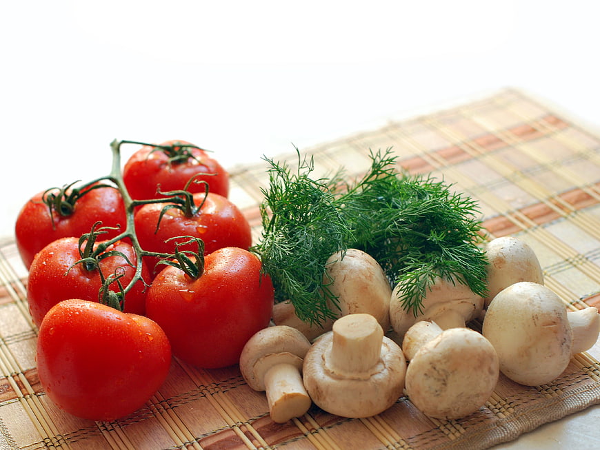 Fresh tomatoes, mushrooms, and dill on bamboo mat