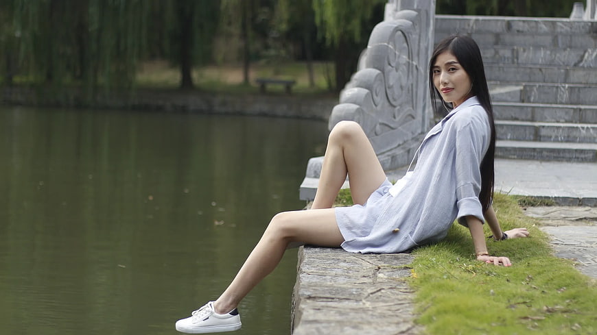 Young Woman in Blue Dress Sitting by Lake