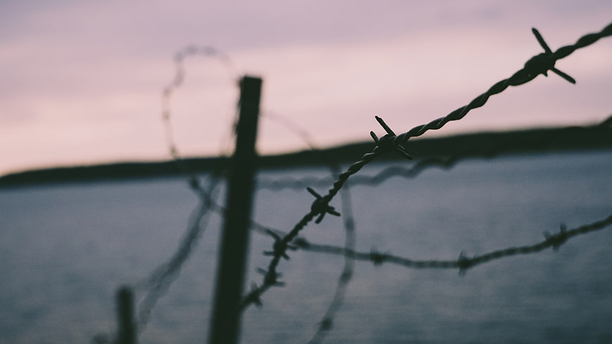 Barbed Wire Fence Silhouette Against Sunset Sky