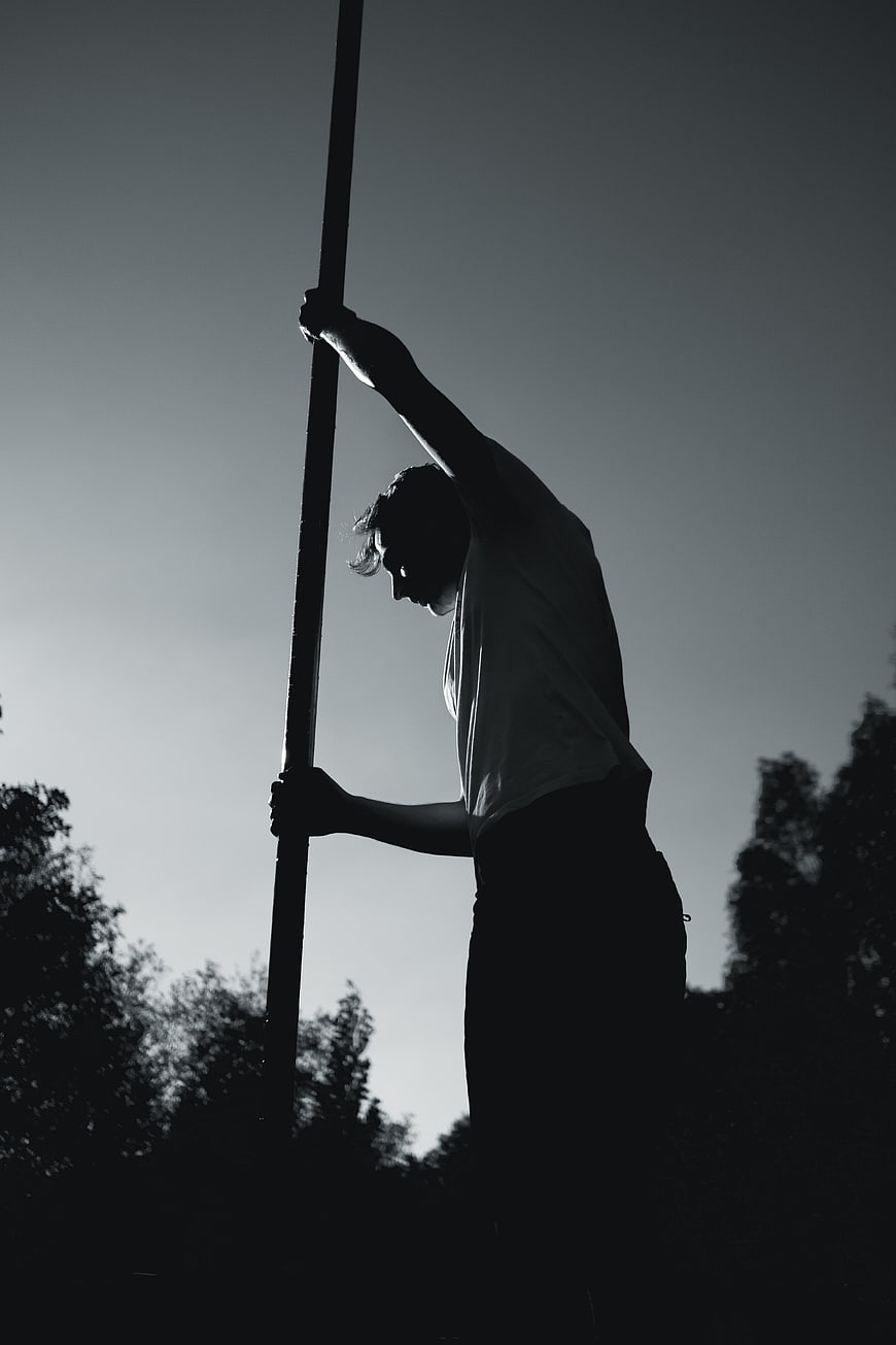 Silhouette of Man Holding Vertical Pole Outdoors