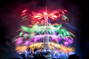 Colorful fireworks exploding around a tall tower at night