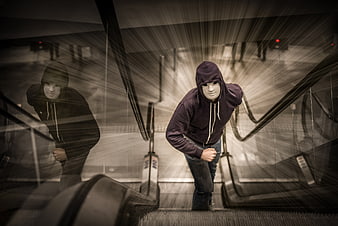 Mysterious hooded figure running on escalator with motion blur