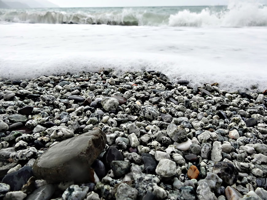 Low angle view of wet pebbles on a rocky beach with ocean waves