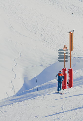 Skier at Mountain Trail Signpost on Snowy Slope