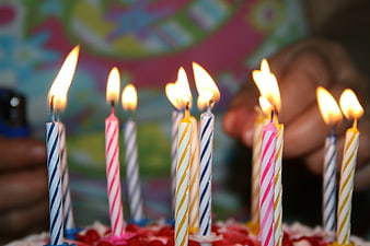 Close-up of lit birthday candles on a colorful cake
