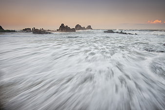 Long Exposure Ocean Waves Crashing on Rocky Beach at Sunset
