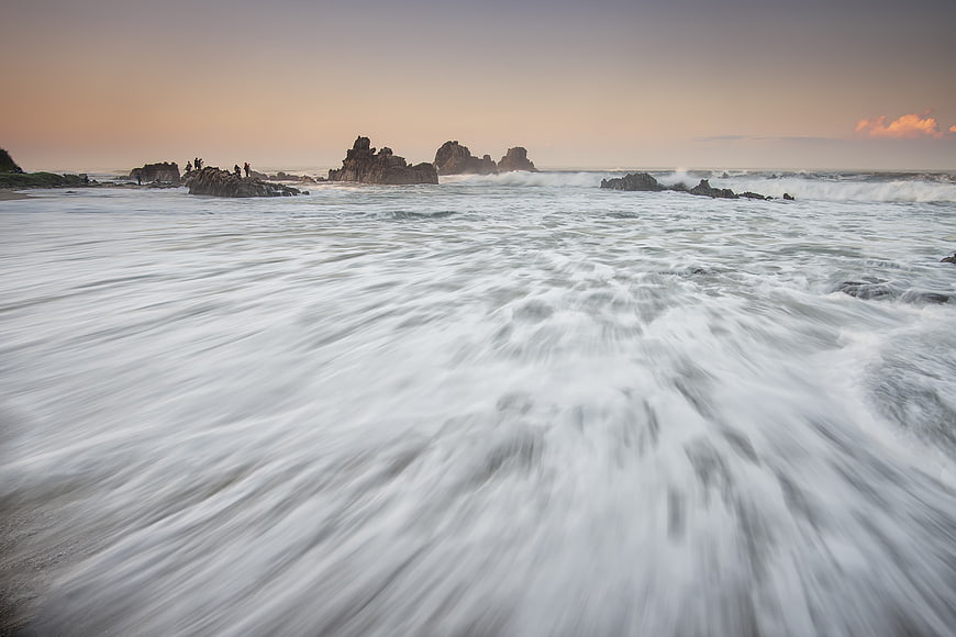 Long Exposure Ocean Waves Crashing on Rocky Beach at Sunset