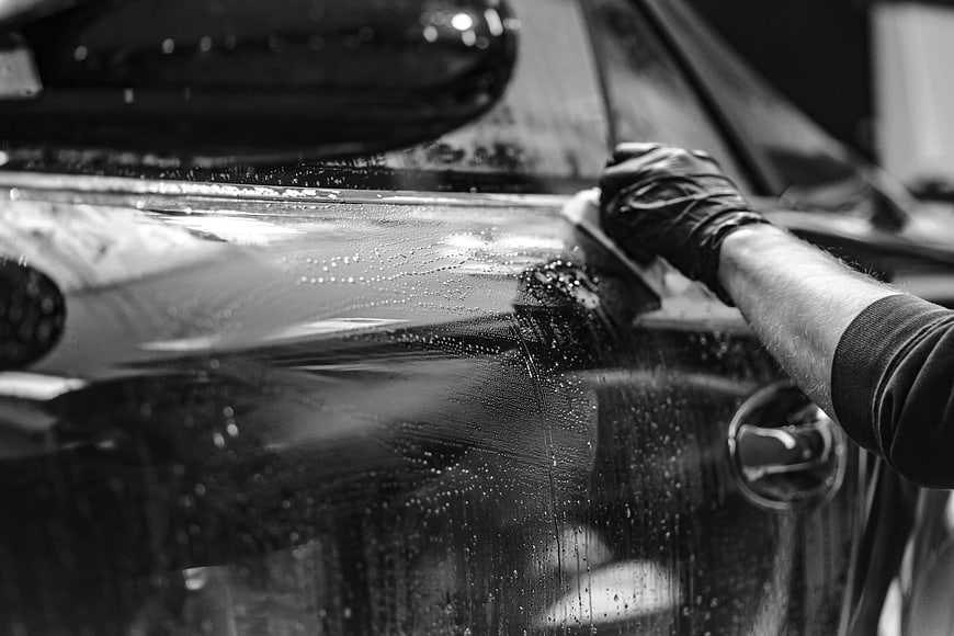 Close-up of hand washing a car with sponge