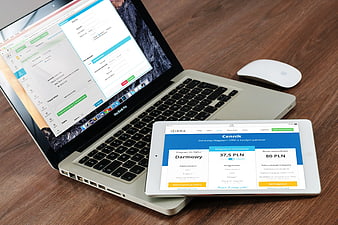 Laptop and tablet displaying accounting software on wooden desk