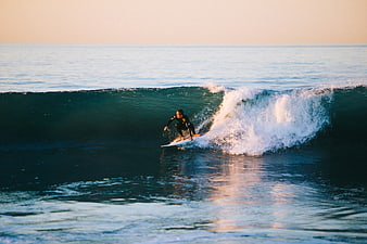 Surfer riding a wave at sunset in the ocean