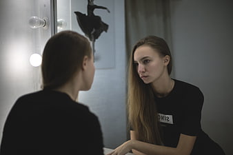 Young woman looking into mirror with serious expression