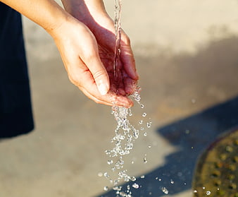 Close-up of hands pouring clear water outdoors