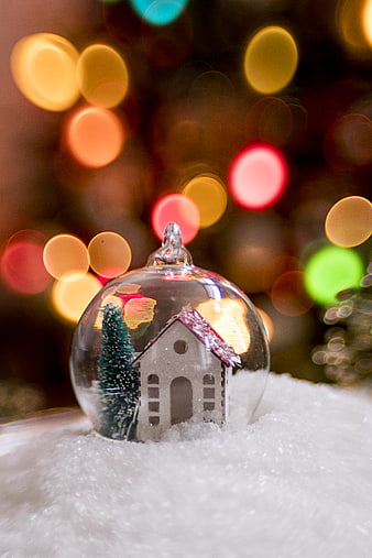 Christmas bauble with miniature house and tree in snow