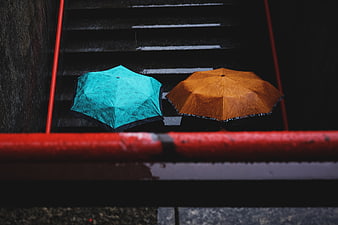 Two colorful umbrellas on wet stairs in the rain