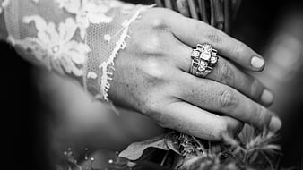 Black and white close-up of wedding ring on hand holding bouquet