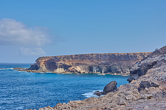 Dramatic rocky coastline with sea caves and blue ocean